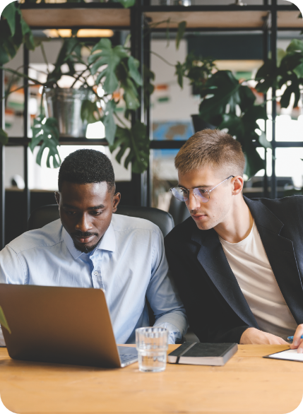 Two men at a table looking at a laptop