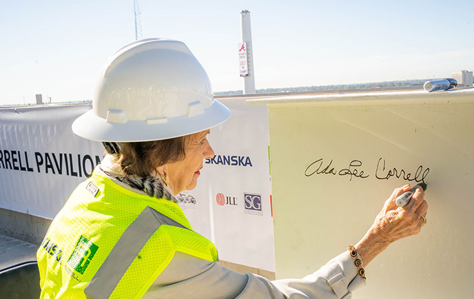 Woman in a hardhat signing a banner