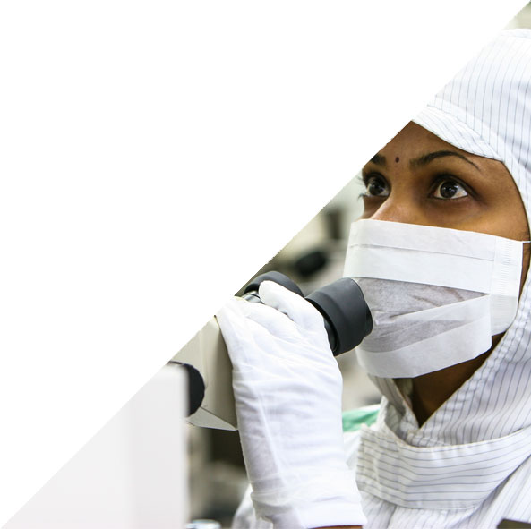 woman in clean room look up from microscope